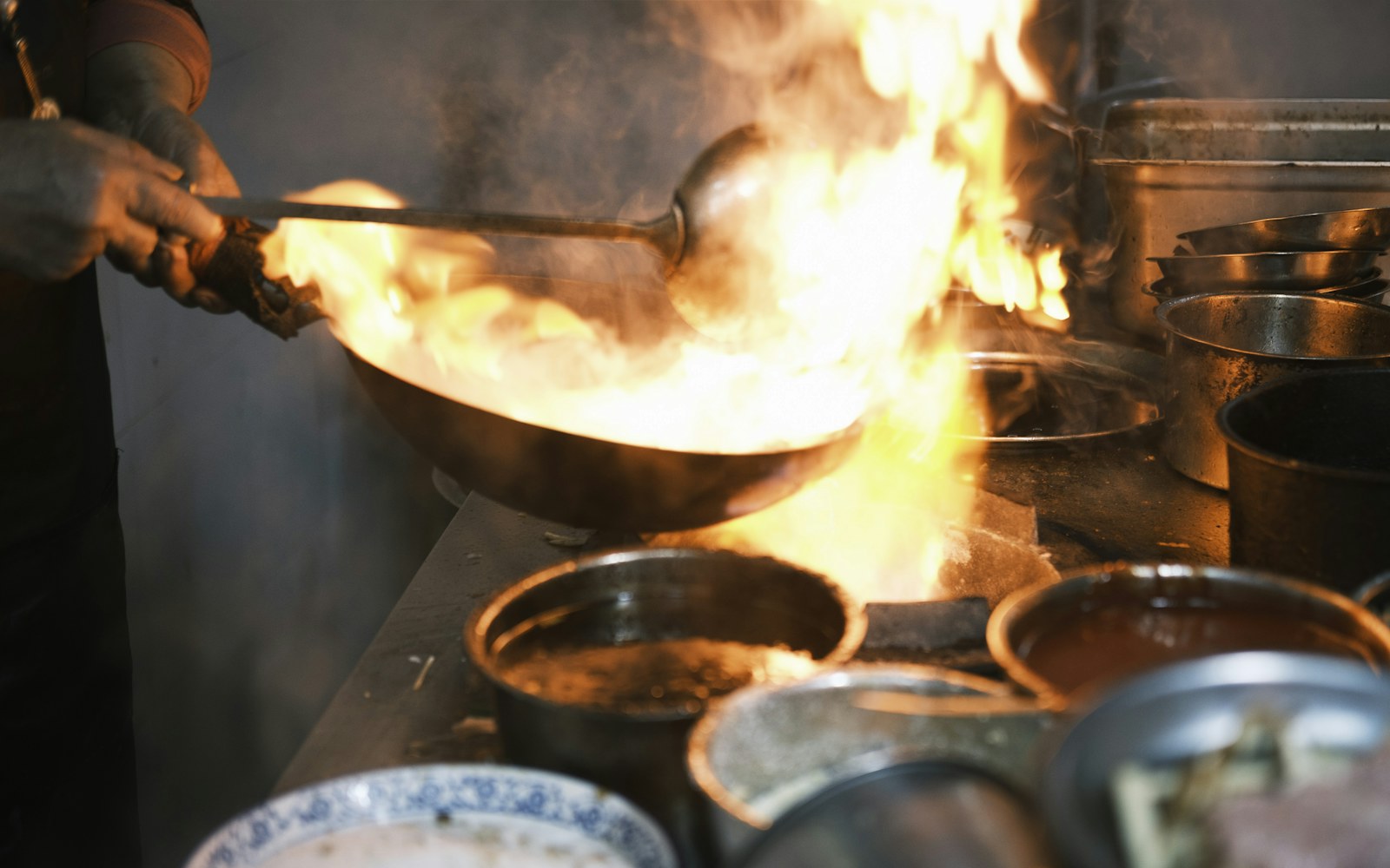 A chef cooking over a lively wok flame